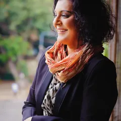 A candid moment of laughter and light. This image captures a natural, unposed smile as the subject looks out a window, bathed in soft, ambient light that highlights her joyful spirit.