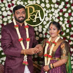 A happy couple during their engagement ceremony. The bride's makeup is traditional, with a touch of turmeric, complementing her purple silk saree and gold jewelry.