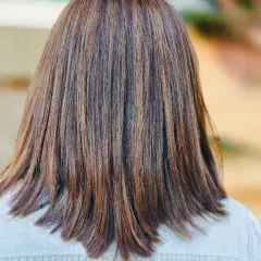 Straight, sleek, and shining with highlights. This look shows how expertly placed highlights can add incredible dimension and texture to a classic shoulder-length cut.