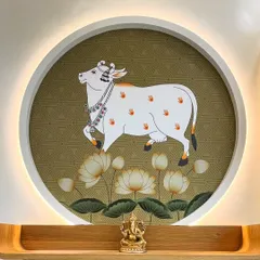 A beautiful detail of a Pichwai wallpaper artwork featuring a sacred cow, framed within a circular niche with backlighting. This creates a divine and artistic focal point in the living room.