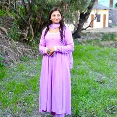 A full-length lifestyle portrait of a woman in a lovely lavender suit, taken in a green, natural setting in the hills. This photo captures a relaxed and happy moment, perfect for personal branding.