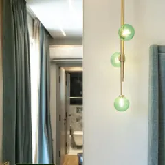 A close-up of a modern pendant light with green glass globes. This fixture acts as a focal point in the bedroom, adding a touch of color and sculptural beauty.