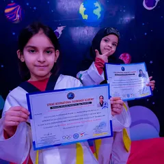 Two of my students proudly show off their official certificates after successfully passing their yellow belt promotion test.