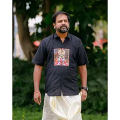 A classic portrait of the model, showcasing the unique graphic on the shirt and the traditional Onam attire.