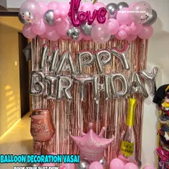 A fun and girly birthday setup with a pink shimmer curtain. The decor includes "Happy Birthday" foil balloons and other party props.