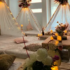 We turn any space into a magical escape. This cozy and luxurious slumber party setup features individual teepees adorned with floral arrangements, fairy lights, and plush floor seating for an unforgettable night in.