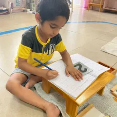 Writing is a natural progression, not a forced exercise. This child is practicing number formation, building on countless earlier activities that strengthened his hand muscles and developed his concentration.