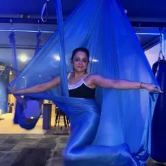 Wrapped in the silk, feeling graceful and strong. The vibrant blue fabric and the member's confident pose capture the empowering atmosphere of our studio.