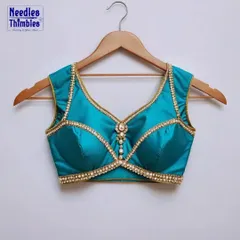 A stunning example of a custom-made blouse. This teal padded blouse features a sweetheart neckline and is embellished with a delicate pearl and stone border for a rich, formal look.