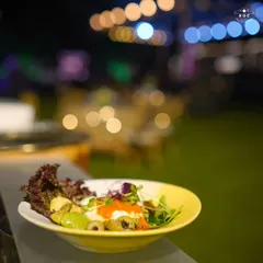 Our Chipotle Bowl is a vibrant and healthy option for any event. Served here against the backdrop of an evening party, it combines fresh greens, beans, corn, and other toppings for a customizable and flavorful meal.