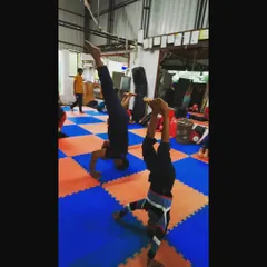 Students practicing their headstands on the mats. Consistent practice is the only way to master balance and make inversions feel natural.