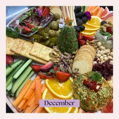 A festive Christmas-themed cheese platter from a December event. It features a cheese ball shaped like a Christmas tree and is surrounded by seasonal fruits and nuts.