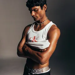 A quiet, introspective moment from the Calvin Klein shoot. The styling is minimal to emphasize the model's form and the classic appeal of the CK tank top, creating a timeless and authentic portrait.
