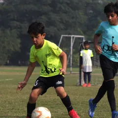 A young player focuses on controlling the ball, showcasing the dribbling skills and concentration we nurture in our youth football leagues. Every touch is a step in their development journey.