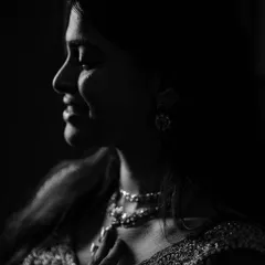 A dramatic low-key portrait in black and white. The careful use of light illuminates the subject's profile and the sparkle of her jewelry, creating a sophisticated and artistic shot.