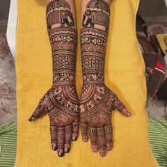 Full coverage bridal mehndi extending up the arms, featuring bands of different traditional patterns. You can see marching elephants, floral vines, and geometric checks, all coming together in a harmonious design.