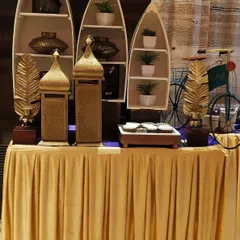 A creative and stylish buffet station from a festive event. The boat shaped shelves, golden decor pieces, and a decorative bicycle add a unique and personalized flair.