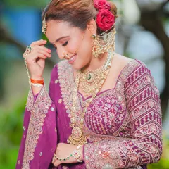 A candid moment capturing the joy of a bride. The look features a classic floral bun and heavy jewelry, balanced with glowing, natural-looking makeup.