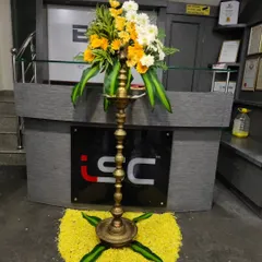 A traditional lamp decorated with fresh flowers, placed at the reception desk for a corporate anniversary celebration.