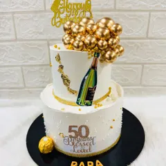 "50 Years Blessed & Loved." This two-tiered cake for a father's 50th birthday features a champagne bottle theme, golden balloon accents, and a heartfelt message.