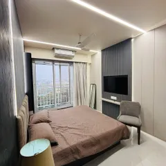 I designed this master bedroom to be a cozy retreat. The combination of dark textured wall panels, soft ambient lighting from the ceiling, and an upholstered headboard creates a warm and inviting modern bedroom.