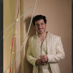 Our client looks radiant in a custom off-white Indowestern jacket set. The entire ensemble, including the jacket, waistcoat, and trousers, features geometric sequin embroidery for a shimmering, celebratory look.