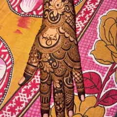 A close up of a personalized henna design with the name 'Shoaib' written in beautiful Arabic calligraphy on the palm.