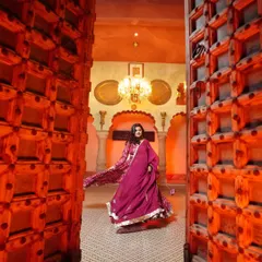 A dramatic entrance. The bride-to-be twirls in her magnificent magenta lehenga, framed by grand wooden doors, creating a powerful and regal portrait.