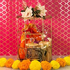 This regal gold cage hamper is one of my signature Diwali offerings. Wrapped with fairy lights and topped with fresh flowers, it holds a jar of almonds, aromatic dhoop cones, and indulgent almond rocks.