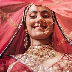 A joyful smile from the bride, Bhavita, from under her veil. This close-up captures her happiness and the intricate details of her bridal look.