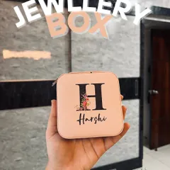 This personalized jewellery box is perfect for keeping your accessories organized. It features a custom initial "H" with a floral design and the name "Harshi" printed below, all on a lovely pale pink travel case.