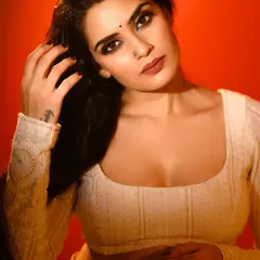 A close-up portrait with a strong, intense expression against a bold red background. The shadows on the face add depth and a cinematic quality to the shot.
