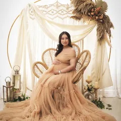 A dreamy boho setup featuring a large golden ring with macrame and pampas grass. The mom-to-be looks absolutely ethereal in a flowing peach gown.