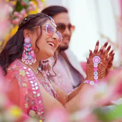 A candid moment of pure laughter. This shot, framed by flowers, captures the bride enjoying her Mehendi ceremony. It’s these unscripted, happy moments that make the best memories.