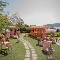A winding stone path through the 'Pyaar ka Pind' setup, leading guests past colorful food stalls and seating areas, all with a view of the lake.