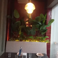 A cozy restaurant booth with a custom-lit planter box filled with artificial tropical plants. This creates an intimate and lush dining experience for patrons.