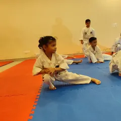 A young student practices a low stance during warm-ups, building strength and flexibility from an early age.