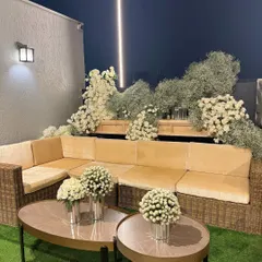An outdoor lounge area transformed into a white floral paradise. We used cascading arrangements of white roses and baby's breath to create a dreamy backdrop for the comfortable wicker seating, perfect for an evening of celebration.