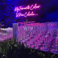 Another fun neon sign, 'My Favourite Colour Is Pina Colada', glowing above the bar, adding a playful and personal touch to the party decor.