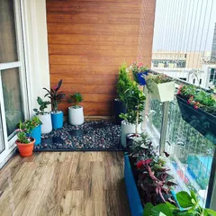 This balcony garden uses a combination of floor planters and railing boxes to create multiple layers of green. The design provides a beautiful city view framed by flowers and foliage, making it a perfect urban retreat.