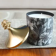 A close-up of our Monochrome Forest scented candle. The black and white palm print and gold pineapple lid create a look of pure tropical sophistication.
