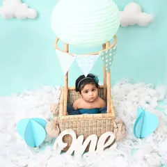Up, up, and away! This sweet baby girl is ready for an adventure in her very own hot air balloon. This whimsical setup is a creative and beautiful way to mark a first birthday.