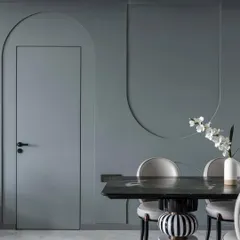 The 'House of Arcs' lives up to its name with curves and arches integrated throughout the design. Here, a flush door is set within a wall featuring decorative arched grooves, creating a subtle yet cohesive design language.