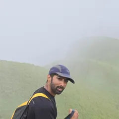 A close-up shot during the Netravathi peak trek, equipped with a backpack and trekking pole.