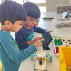 Our summer camps are designed to be interactive and engaging. Here, two students use a tablet to program their LEGO robot, learning the basics of coding and seeing their commands execute in real-time.