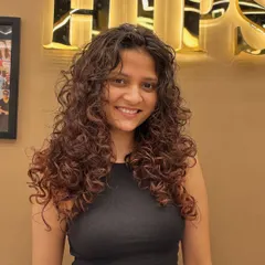 A smiling client, confident and happy with her curly hair makeover. The style is full of life and personality.