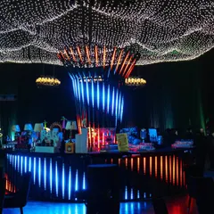 The central bar is a masterpiece of light and design. The illuminated base and a canopy of fairy lights create a vibrant hub for the celebration.