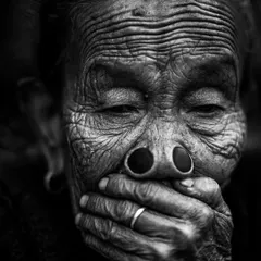 A powerful black and white portrait of an Apatani woman from Arunachal Pradesh. The texture of her wrinkled skin and the traditional nose plugs tell a story of a disappearing culture.
