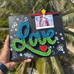 A "Love" themed string art piece with a clip to hold a special photo. The board is decorated with cute doodles, making it a fun and romantic gift.