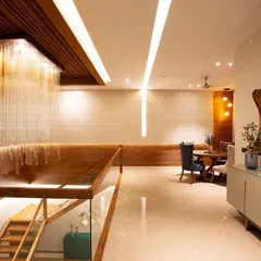 In this residential foyer, light becomes the jewellery of the architecture. A cascading crystal chandelier appears to pour down the stairwell, creating a breathtaking first impression. This is complemented by integrated linear lighting and subtle wall washing to create layers of warmth and sophistication.